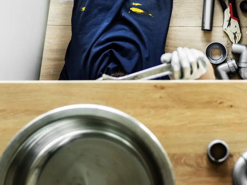 Plumber fitting pipework under a kitchen sink System Servicing Lincoln